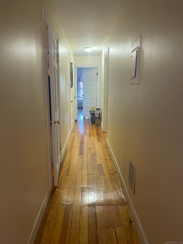 corridor with electric panel and hardwood / wood-style flooring