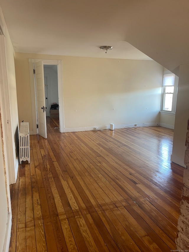 spare room with radiator heating unit and hardwood / wood-style floors