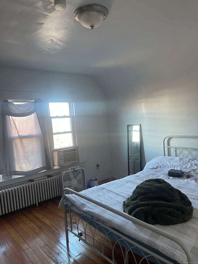 bedroom with radiator heating unit, dark hardwood / wood-style flooring, vaulted ceiling, and cooling unit