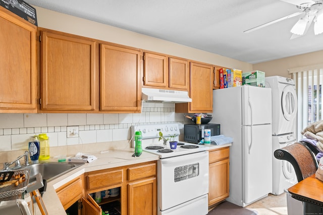 kitchen with decorative backsplash, sink, stacked washer / dryer, white appliances, and ceiling fan