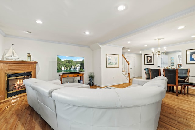 living room with an inviting chandelier, light hardwood / wood-style flooring, and crown molding