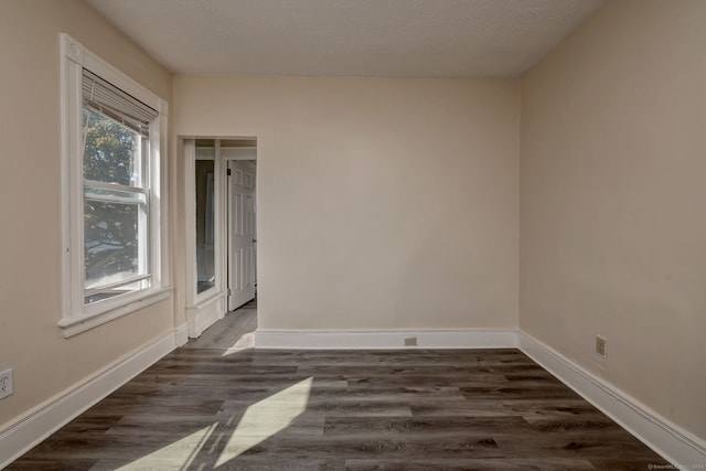 empty room with a textured ceiling and dark hardwood / wood-style floors