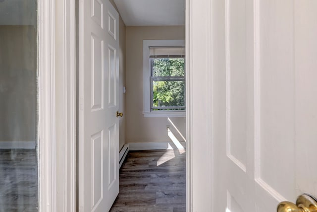 corridor featuring a baseboard heating unit and dark hardwood / wood-style flooring