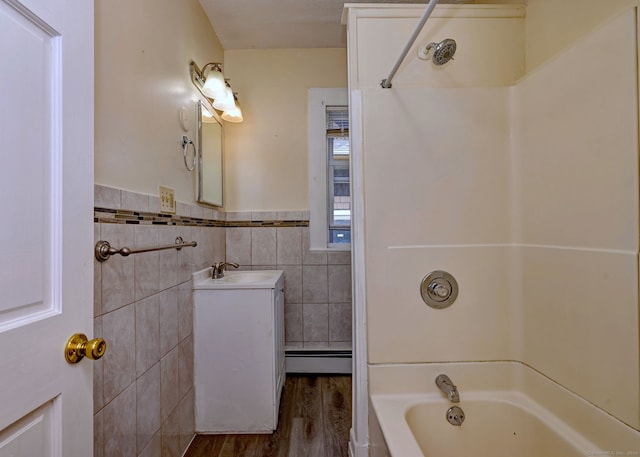 bathroom with wood-type flooring, a baseboard heating unit, tile walls, bathtub / shower combination, and vanity