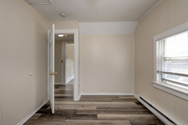 spare room with dark hardwood / wood-style floors, wooden walls, and baseboard heating