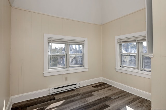 spare room with dark wood-type flooring, a baseboard radiator, and plenty of natural light