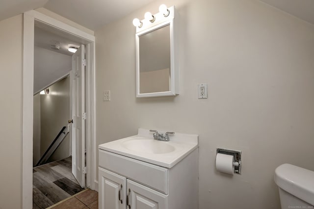 bathroom featuring toilet, vanity, and vaulted ceiling