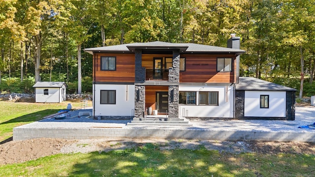 view of front of house featuring a front yard and a storage shed