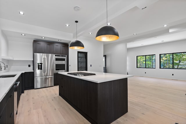 kitchen featuring sink, light hardwood / wood-style flooring, pendant lighting, a kitchen island, and appliances with stainless steel finishes