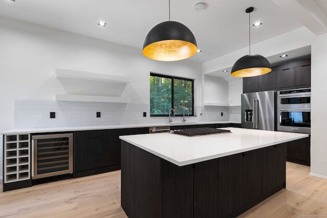 kitchen with appliances with stainless steel finishes, light wood-type flooring, tasteful backsplash, and hanging light fixtures