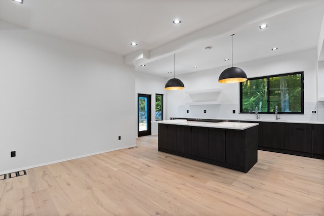 kitchen featuring tasteful backsplash, a center island, pendant lighting, and light wood-type flooring