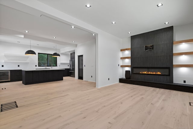 living room featuring a fireplace, beverage cooler, and light hardwood / wood-style floors