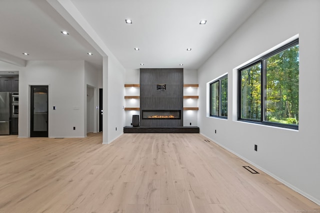 unfurnished living room featuring a large fireplace and light hardwood / wood-style floors