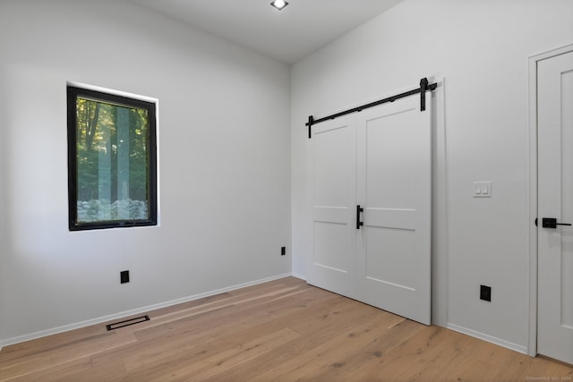 spare room with a barn door and light hardwood / wood-style flooring