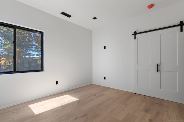 spare room featuring a barn door and light wood-type flooring