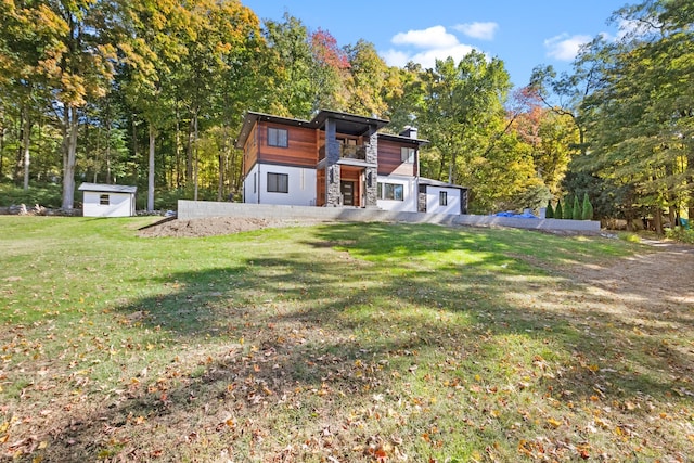 view of front facade featuring a front yard and a storage shed