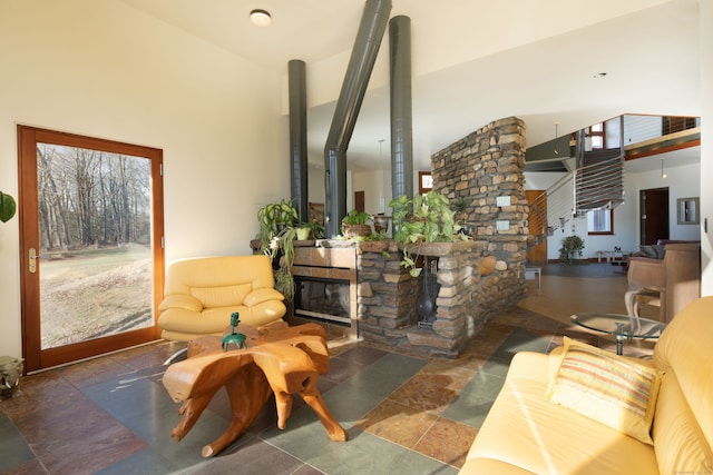 living room with a towering ceiling and a stone fireplace