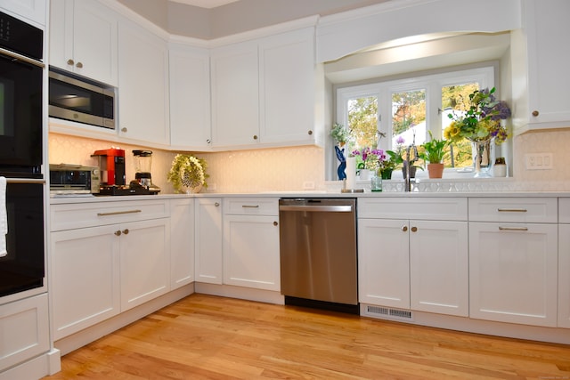 kitchen featuring white cabinets, appliances with stainless steel finishes, and light hardwood / wood-style floors