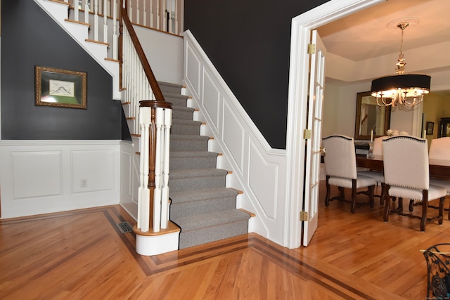 staircase featuring hardwood / wood-style flooring and a notable chandelier