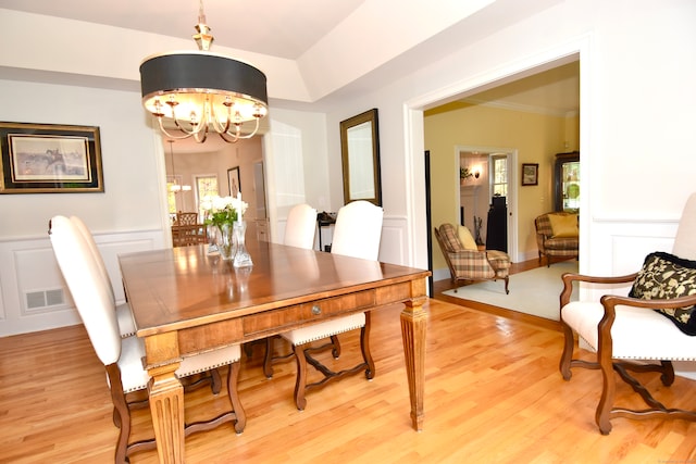 dining space featuring wood-type flooring, crown molding, and a chandelier