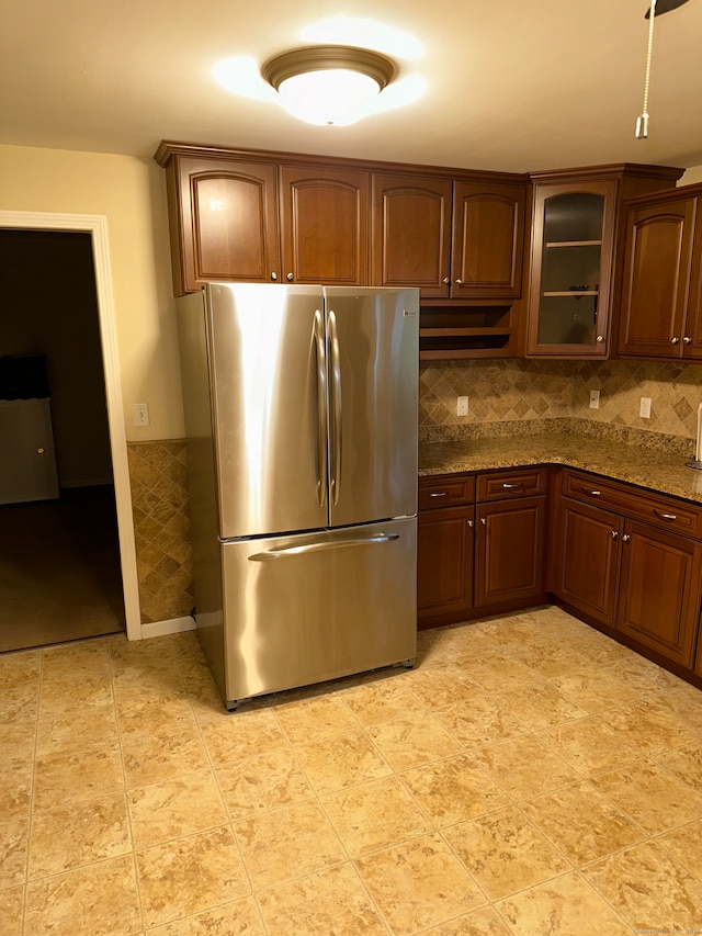 kitchen featuring stone counters, decorative backsplash, and stainless steel refrigerator