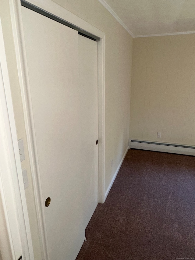 interior space with crown molding, a baseboard heating unit, and dark colored carpet