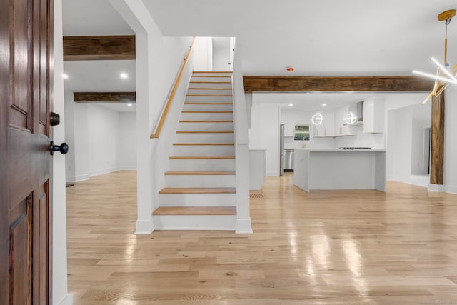 staircase with hardwood / wood-style floors and beam ceiling