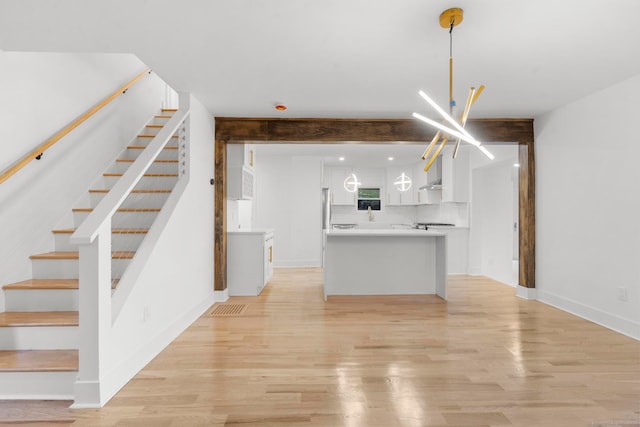 kitchen with pendant lighting, light wood-type flooring, white cabinetry, and a chandelier