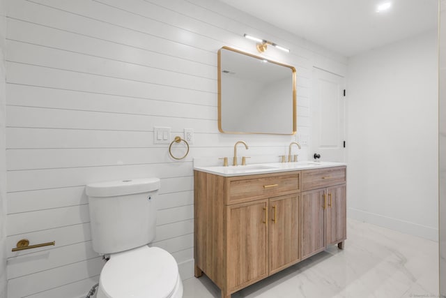 bathroom with vanity, toilet, and wood walls