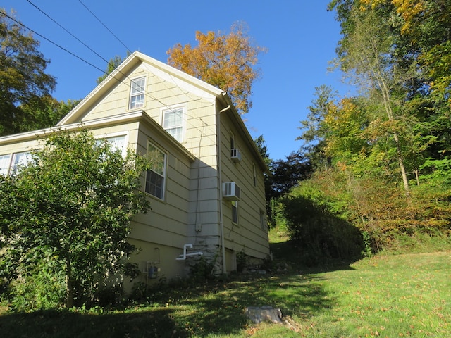 view of side of property with a lawn and a wall mounted air conditioner