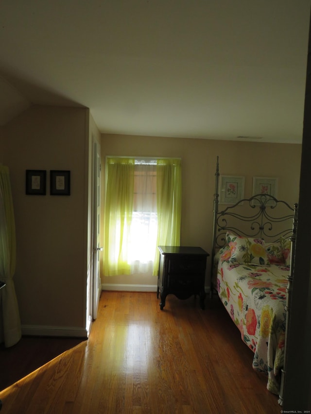 bedroom with wood-type flooring and vaulted ceiling