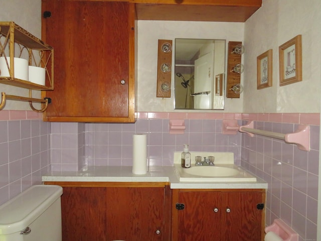 bathroom featuring vanity, tile walls, and toilet