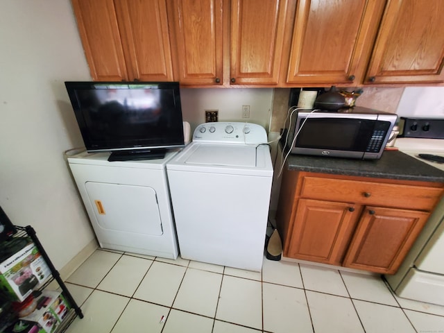 laundry area featuring cabinets, light tile patterned floors, and washing machine and dryer