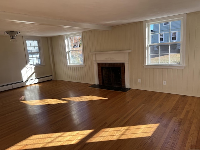 unfurnished living room featuring beam ceiling, a brick fireplace, baseboard heating, and wood finished floors