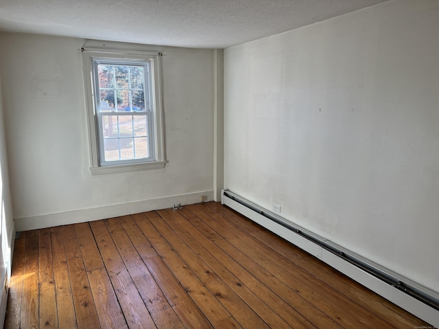 unfurnished room with wood-type flooring, baseboards, baseboard heating, and a textured ceiling