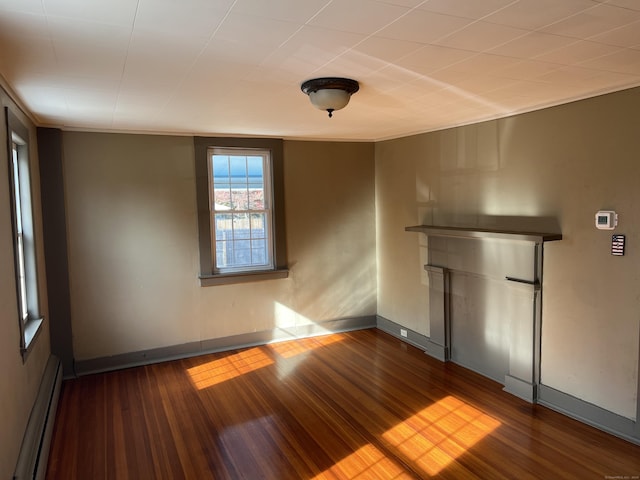 empty room featuring baseboards, crown molding, a baseboard heating unit, and wood finished floors