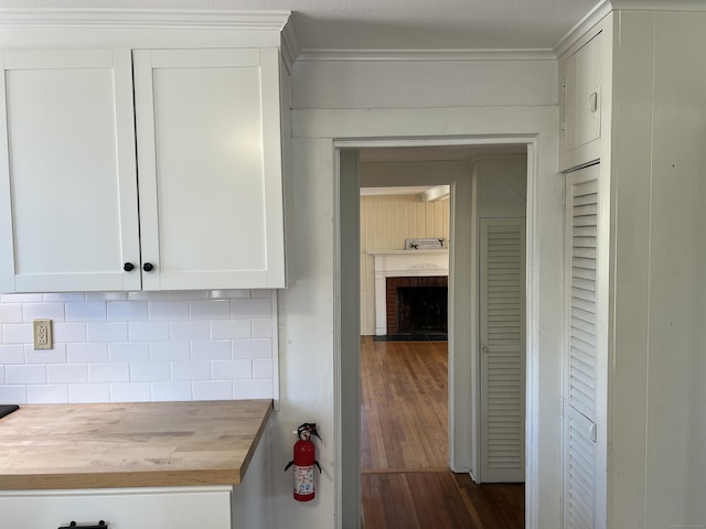 kitchen featuring dark wood finished floors, a fireplace, wooden counters, decorative backsplash, and white cabinetry