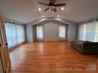 unfurnished living room featuring baseboard heating, a healthy amount of sunlight, vaulted ceiling, and light hardwood / wood-style flooring