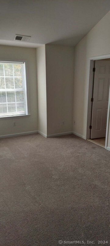 spare room featuring vaulted ceiling and light carpet