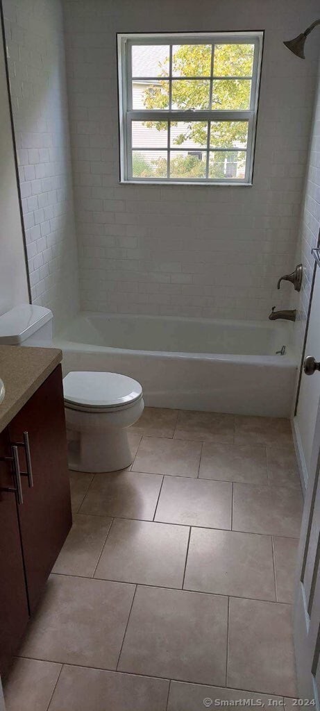 full bathroom with a healthy amount of sunlight, vanity, tiled shower / bath, and toilet