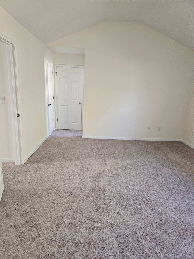 carpeted empty room featuring vaulted ceiling