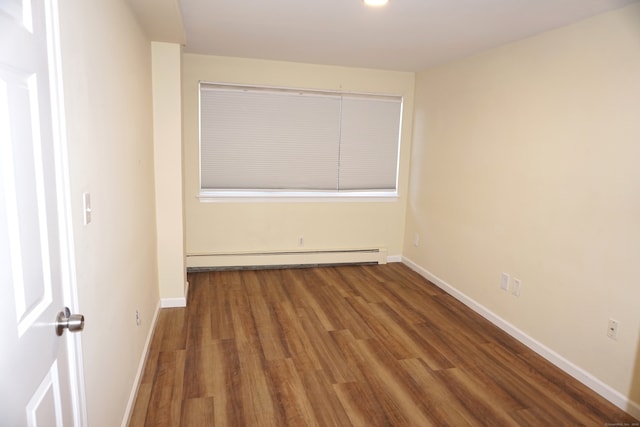 empty room with hardwood / wood-style flooring and a baseboard radiator