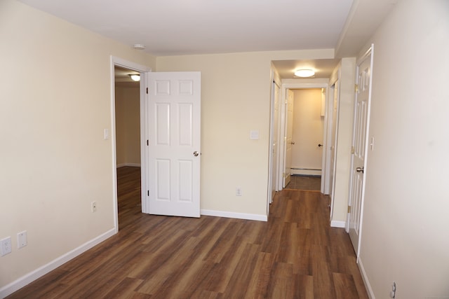 unfurnished bedroom featuring baseboard heating and dark wood-type flooring