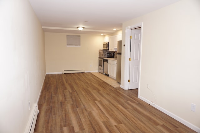 interior space with white cabinetry, light hardwood / wood-style floors, appliances with stainless steel finishes, and baseboard heating