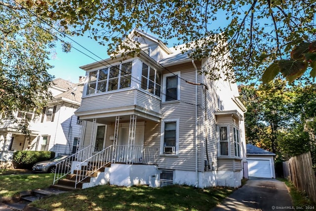 view of front of house featuring a front lawn, a porch, a garage, cooling unit, and an outdoor structure