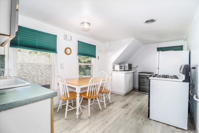 kitchen with white appliances, light hardwood / wood-style floors, and white cabinets