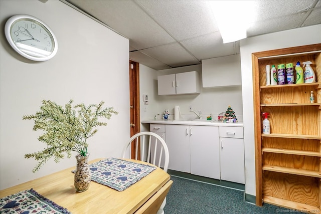 kitchen with a drop ceiling, white cabinetry, and sink