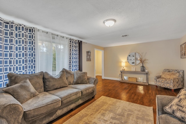 living room with visible vents, a textured ceiling, baseboards, and wood finished floors