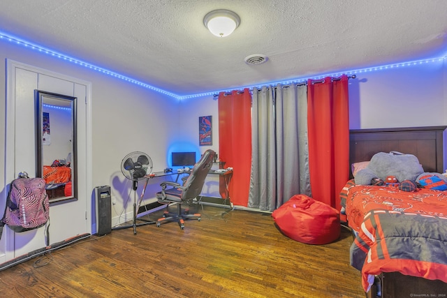 bedroom with visible vents, a textured ceiling, and wood finished floors