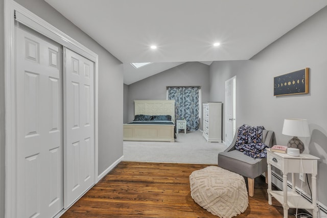 living area featuring vaulted ceiling with skylight, recessed lighting, wood finished floors, and baseboards